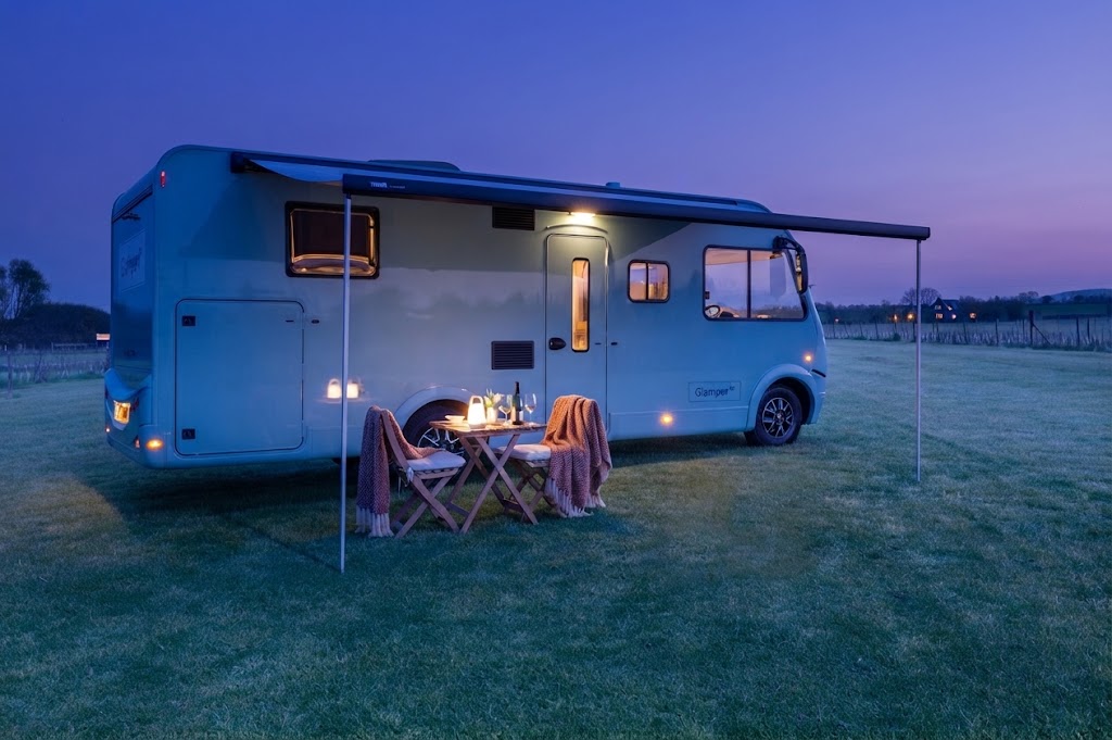 Campingbil med tänd markis i nordisk skymning vid fjäll, roadtrip-glamping i Norge