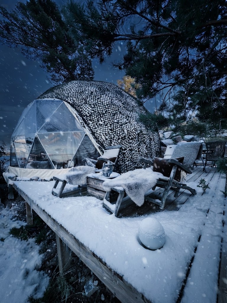 Kupoltält i snöig skog utanför Borås med varmt ljus inifrån
