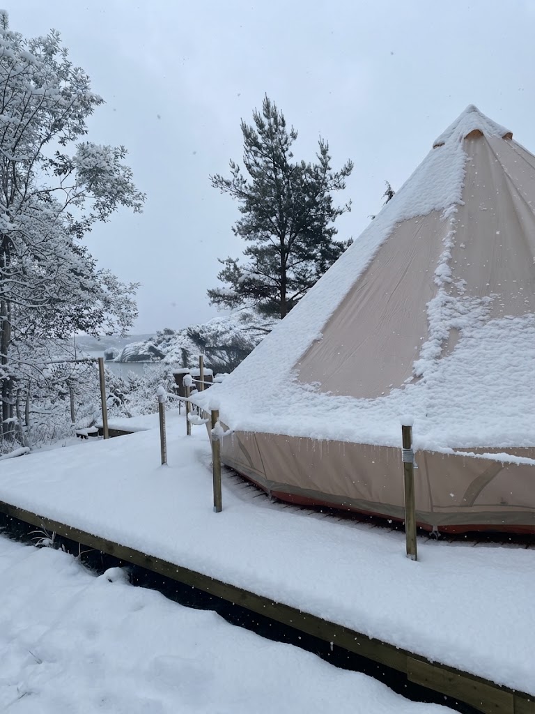 Tipitält på trädäck i skogsglänta med snö, en av Sveriges omtalade glampingplatser
