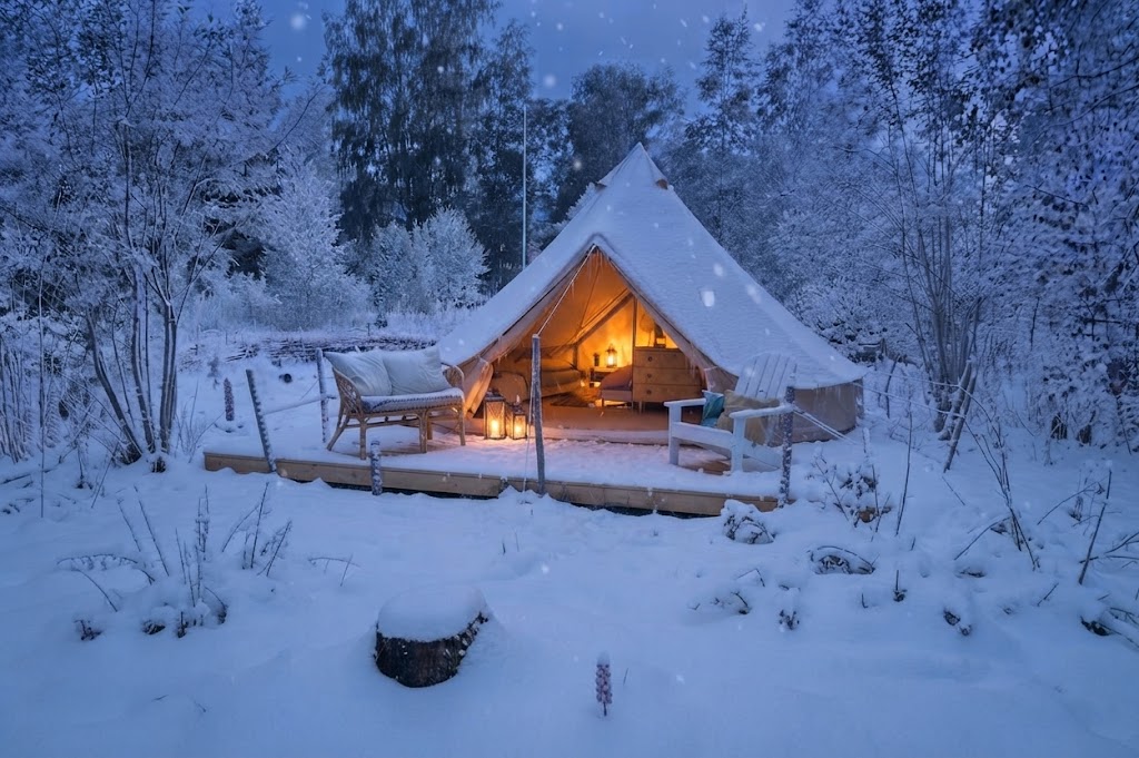 Glampingtält vid sjöstrand i Småland med skog och vatten i bakgrunden