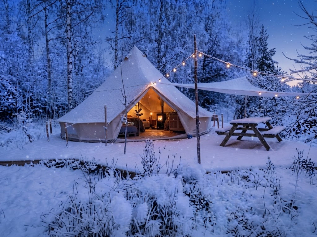 Klassiskt bell tent-glampingtält med ljusslingor i skymningen på svensk äng
